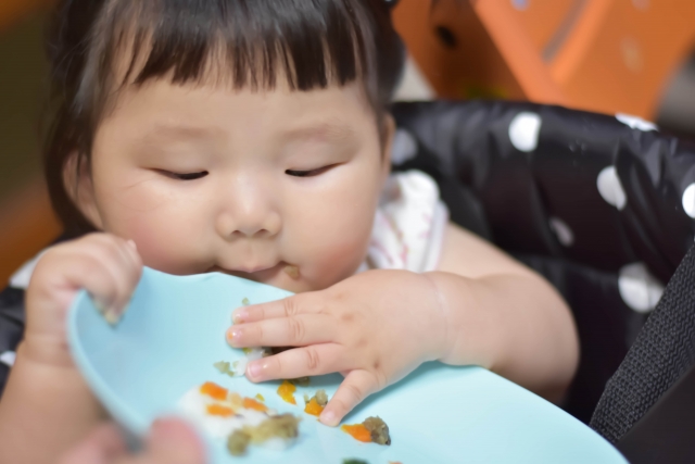 離乳食を手づかみで食べる赤ちゃん